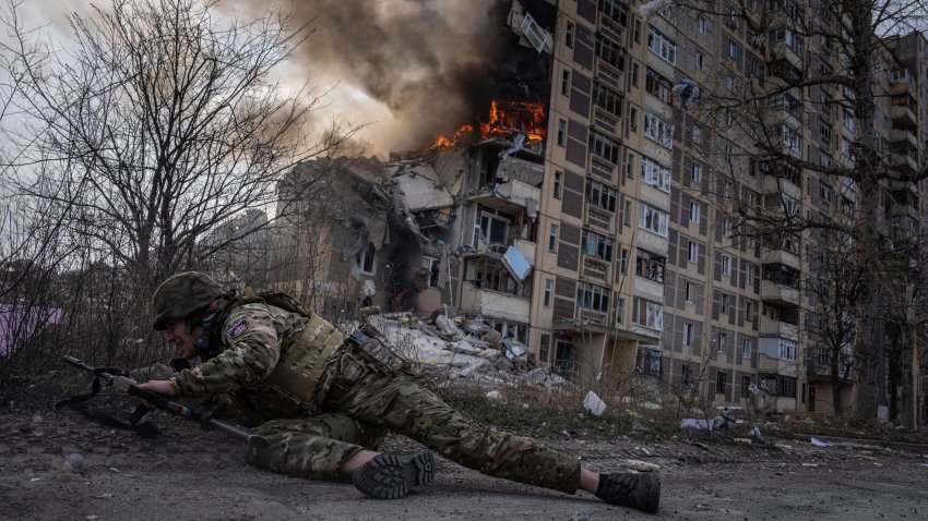 Un agente de la policía de Ucrania se pone a cubierto frente a un edificio en llamas, en Avdiivka, Ucrania, el 17 de marzo de 2023. El segundo año de lucha contra la invasión de Rusia no ha dado tregua ni los soldados ni a la población civil de Ucrania. Los fotógrafos de The Associated Press documentaron los 12 últimos meses de muerte y destrucción, de agonía y dolor — además de los atisbos de alegría — que marcan la vida durante una guerra. (AP Foto/Evgeniy Maloletka)